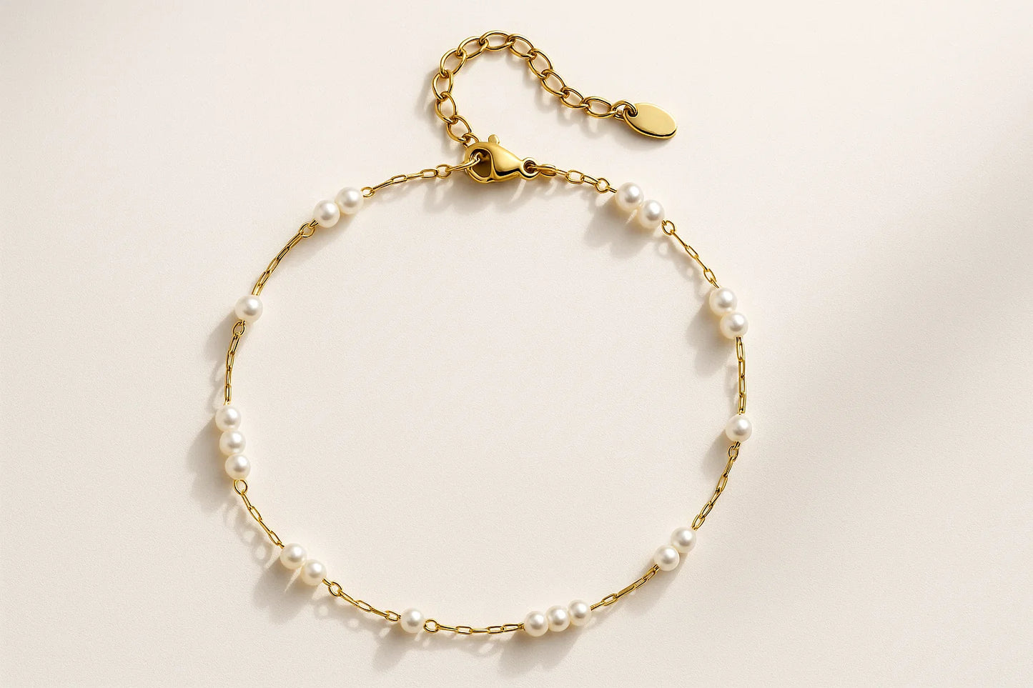 Gold bracelet with pearl beads on a light beige background