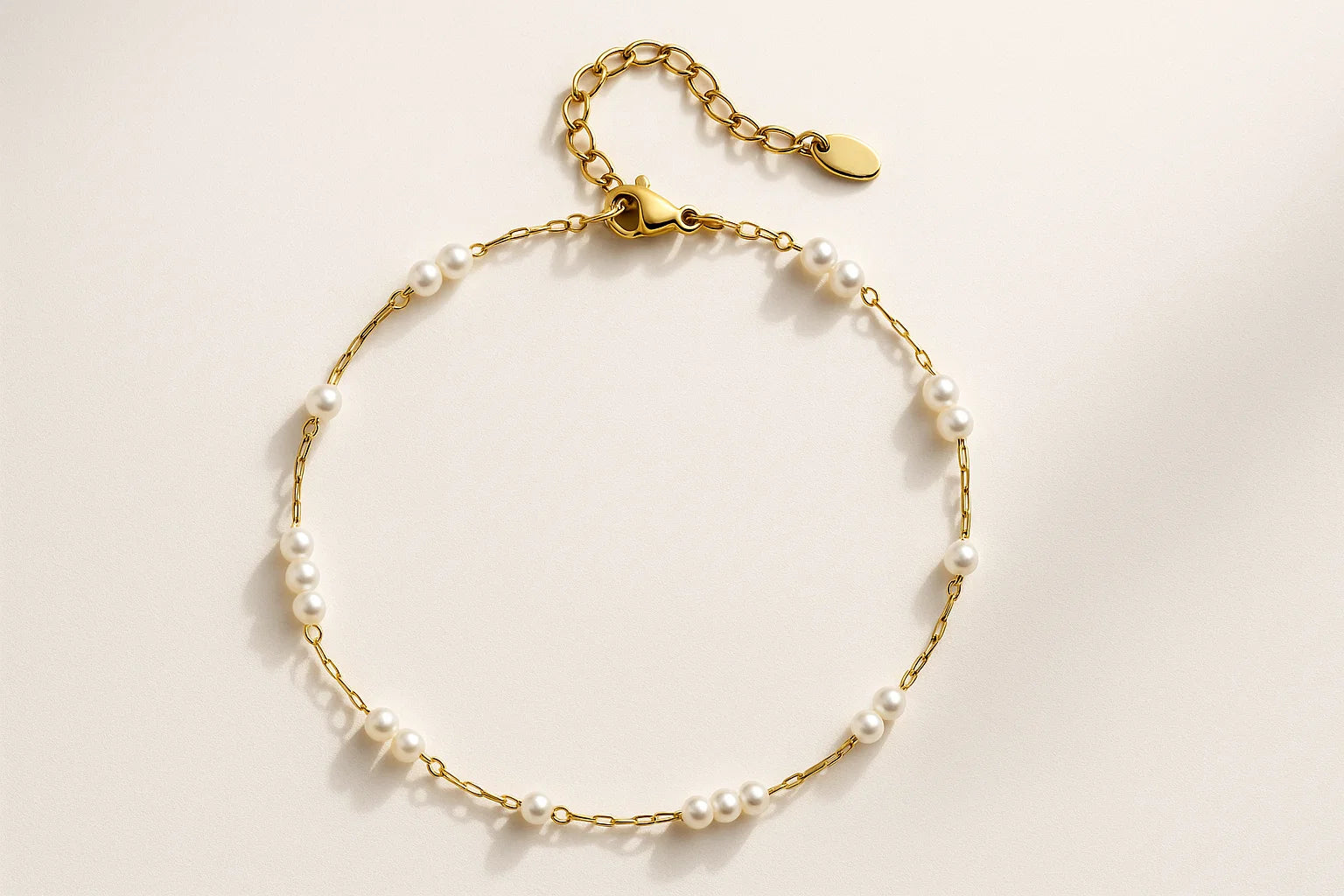 Gold bracelet with pearl beads on a light beige background
